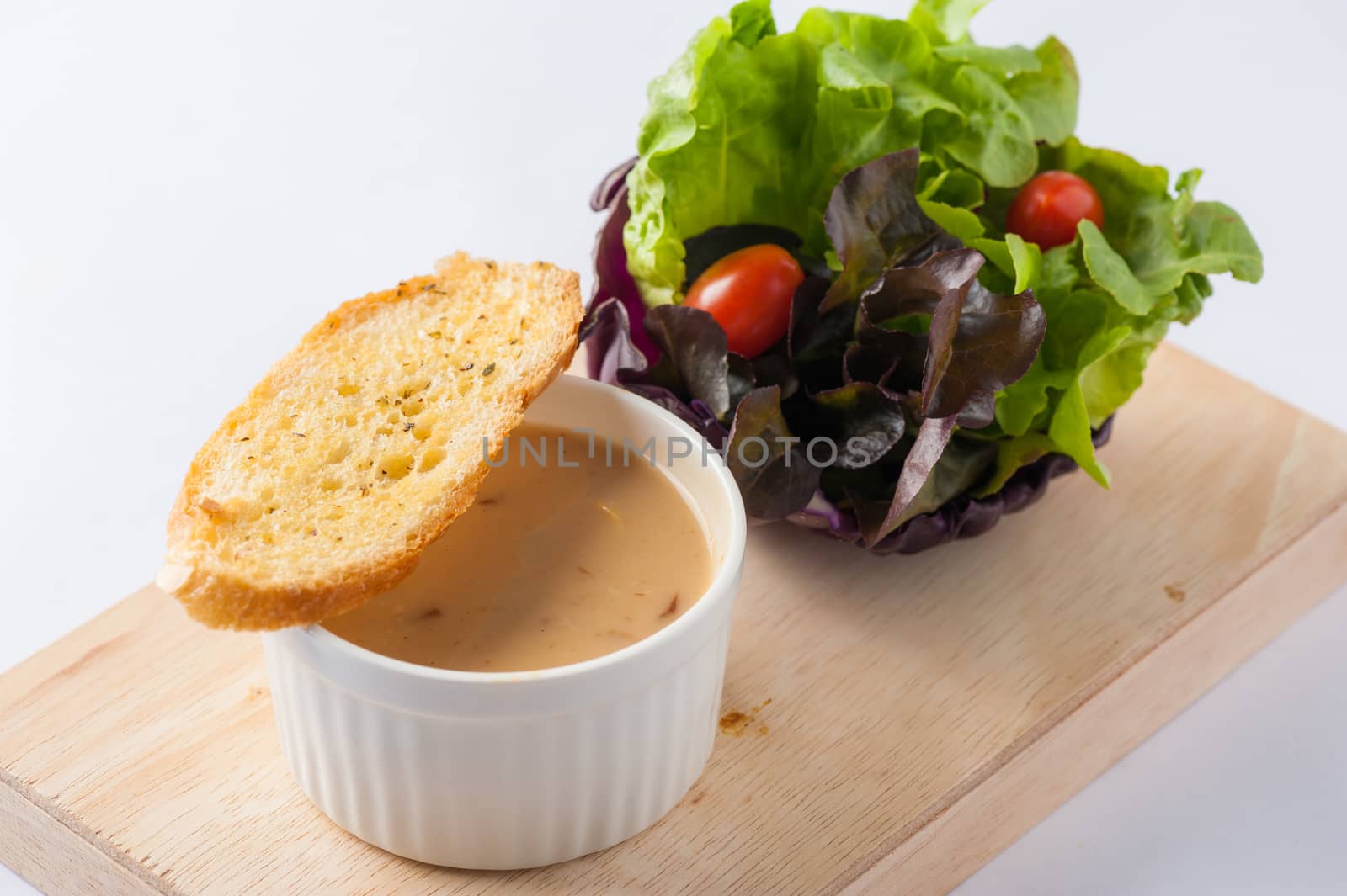 Mushroom soup in ceramic cup with toast and freash vegetables on wood plate. Clean and healthy eating concept food.