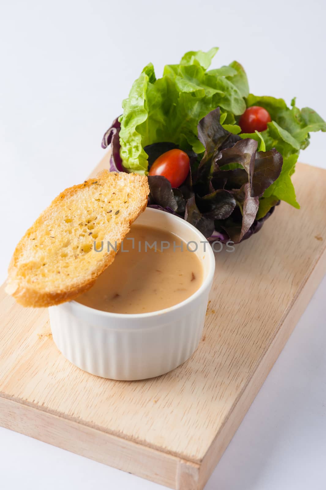 Mushroom soup in ceramic cup with toast and freash vegetables on wood plate. Clean and healthy eating concept food.