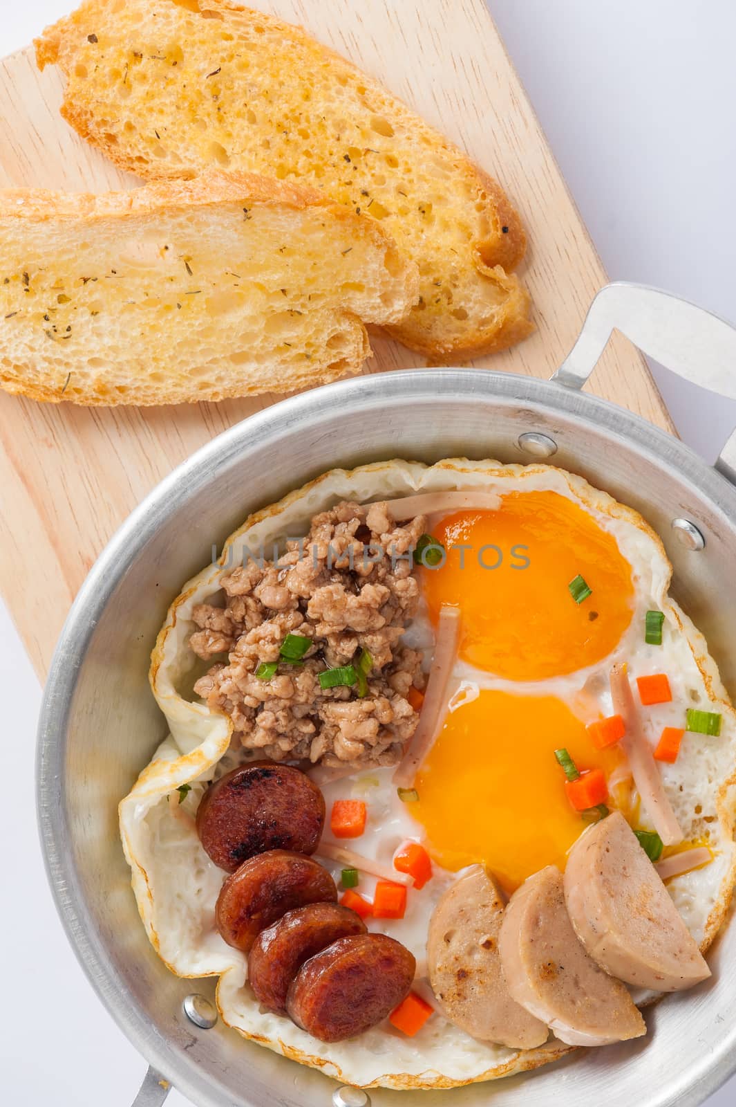 Vietnamese style pan-freid egg with Chinese sausage, minced pork, Vietnamese sausage in metal pan on wood plate with toast