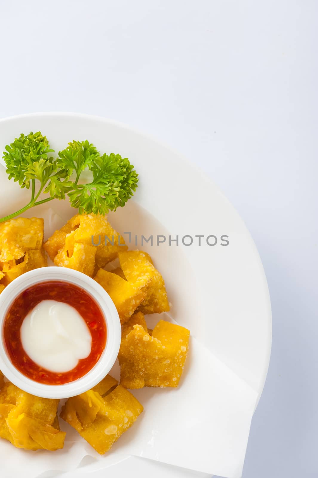 Chinese style deep-fried wonton with sweet and sour sauce in ceramic dish.