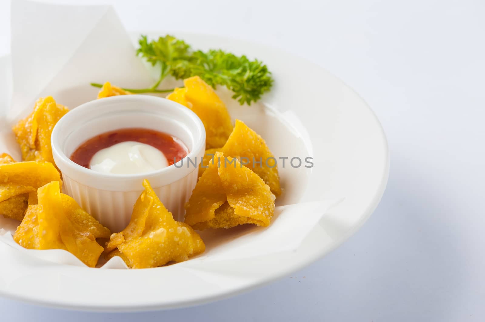 Chinese style deep-fried wonton with sweet and sour sauce in ceramic dish.