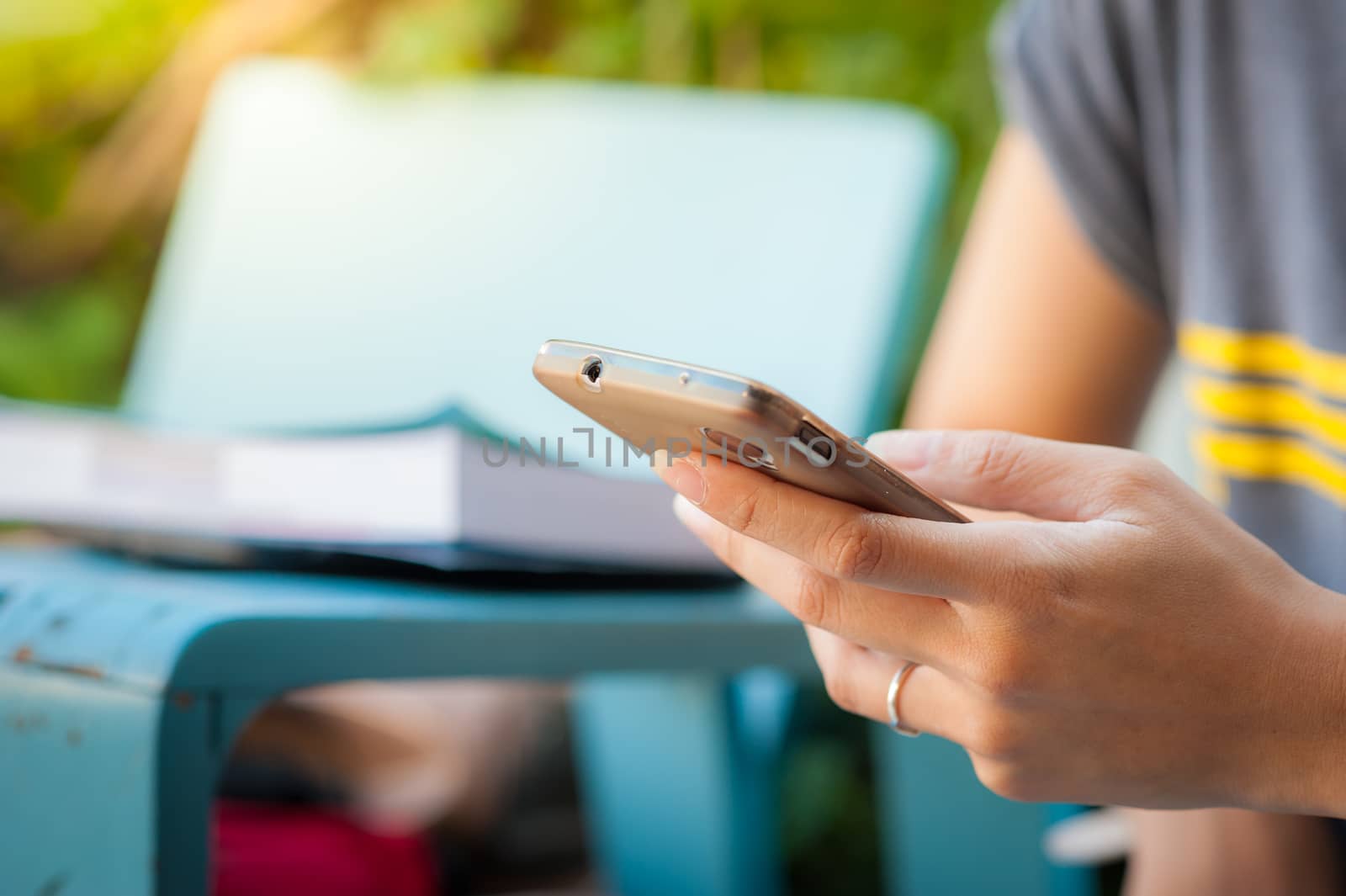 Young woman using smartphone while sitting on wood bench in morning time on weekend