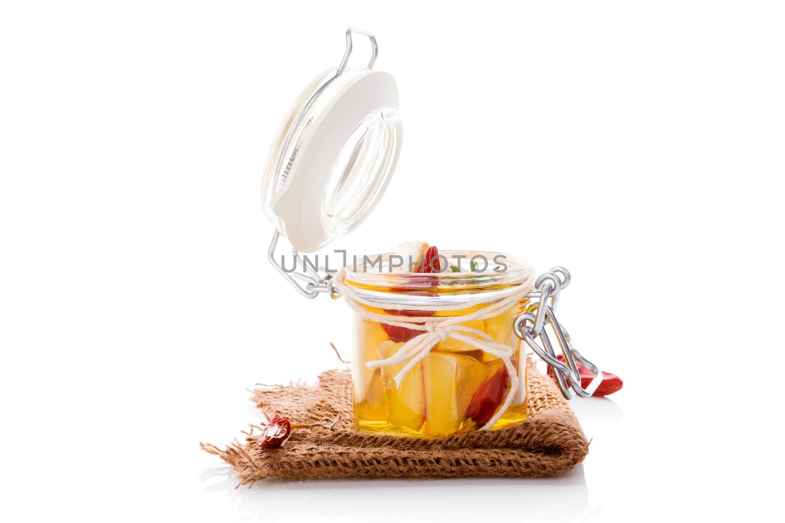 Marinated camembert cheese in glass jar isolated on white background. Culinary cheese eating. 