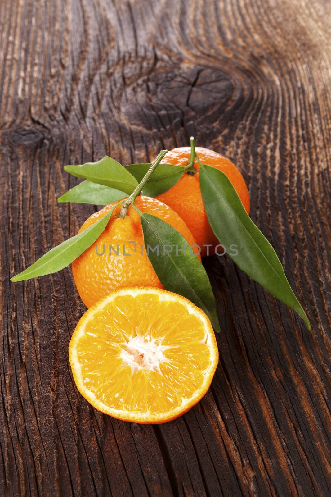 Fresh ripe mandarines with green leaves on wooden table. Organic fresh mandarines, healthy fruit eating. 