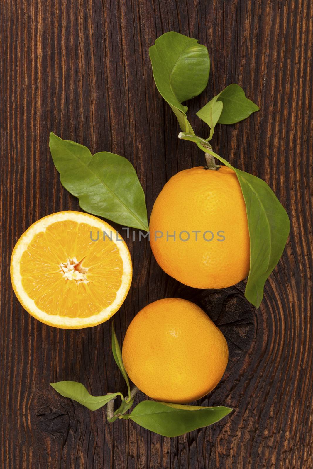 Fresh ripe oranges with green leaves in wooden crate. Organic fresh oranges, healthy fruit eating. 