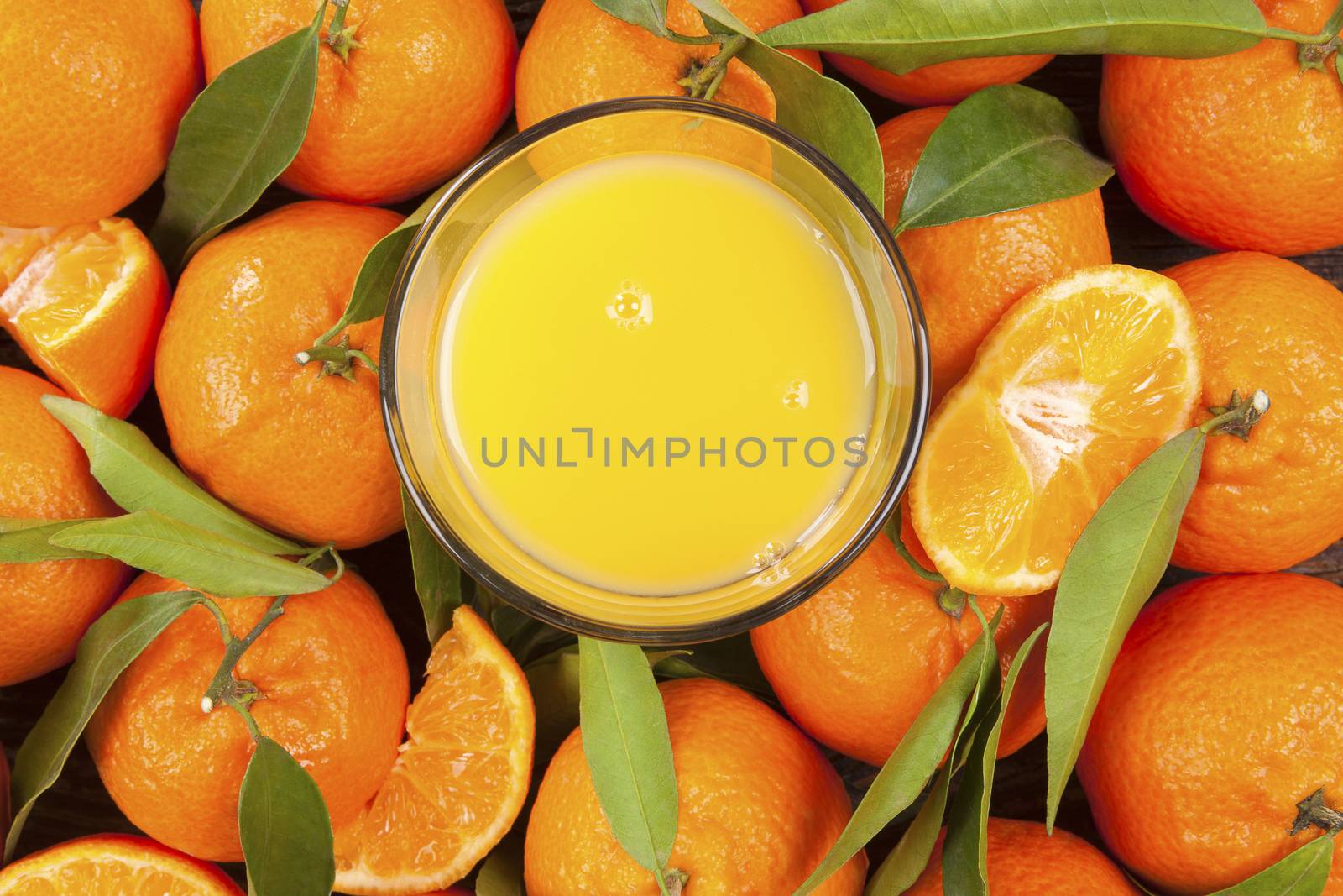 Fresh ripe mandarines with green leaves and orange juice seamless backdrop, flat lay, top view. Organic fresh mandarines, healthy fruit eating. 