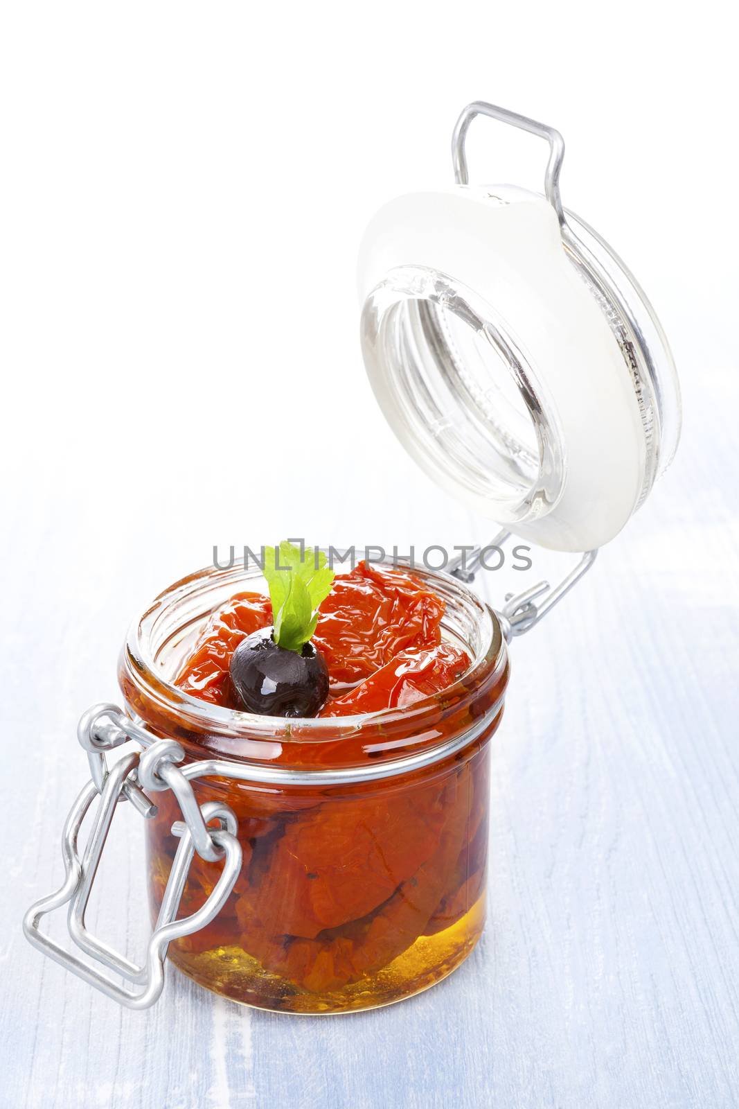 Dry tomatoes in oil in jar on blue wooden background. Culinary eating. 