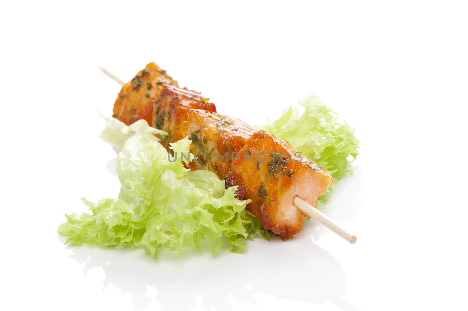 Salmon kebab. Salmon pieces on wooden skewer on green salad isolated on white background. Culinary salmon eating. 