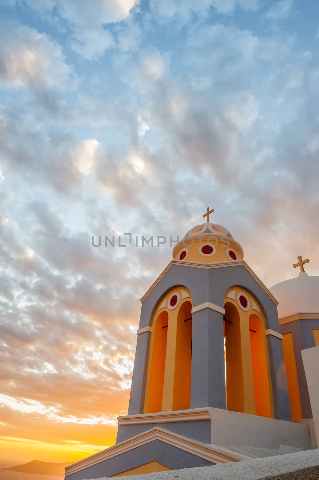 Orthodox church in rays of beautiful sunset. Fira, Santorini Greece. Copyspace