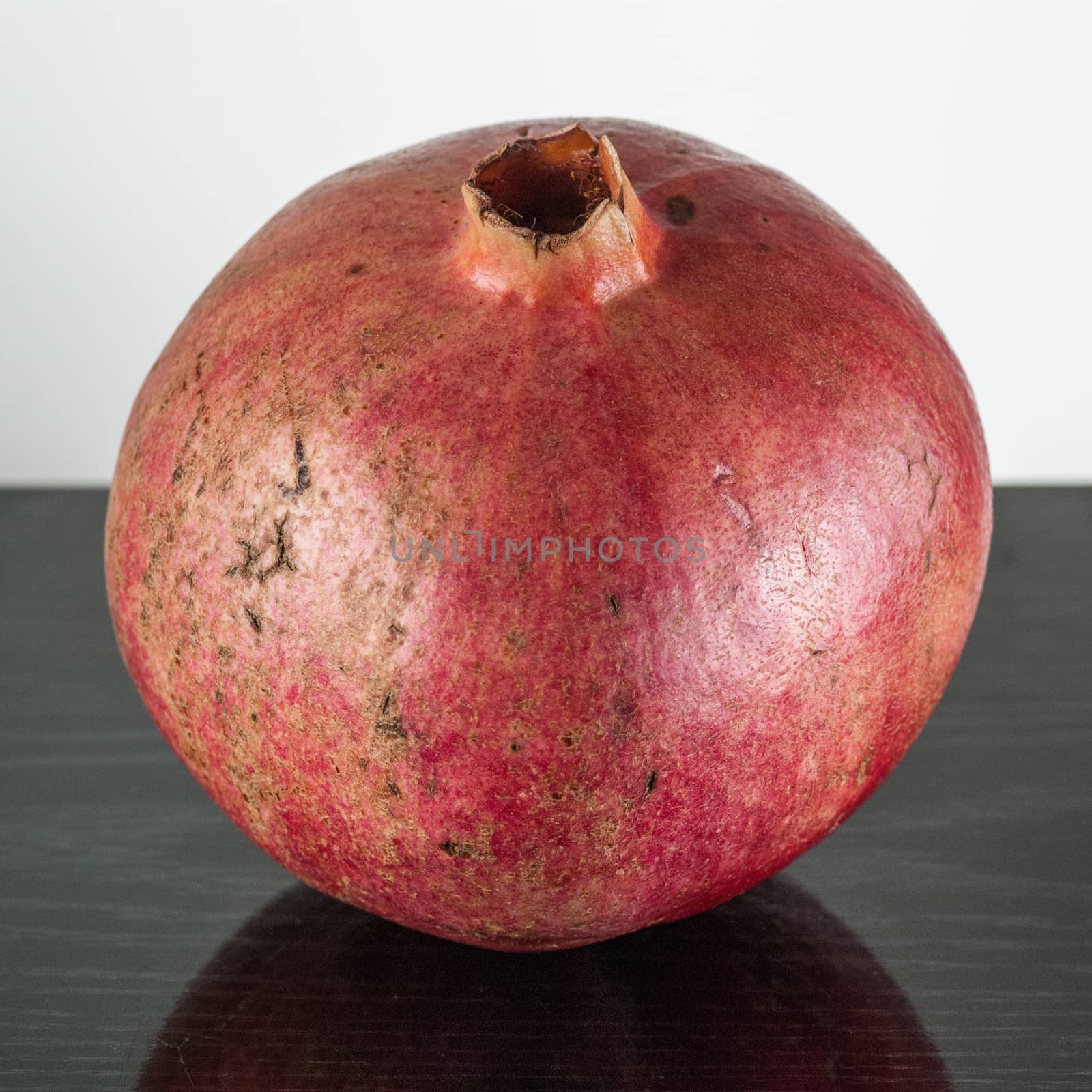  half ripe pomegranate fruit isolated on black wooden plane and white background.