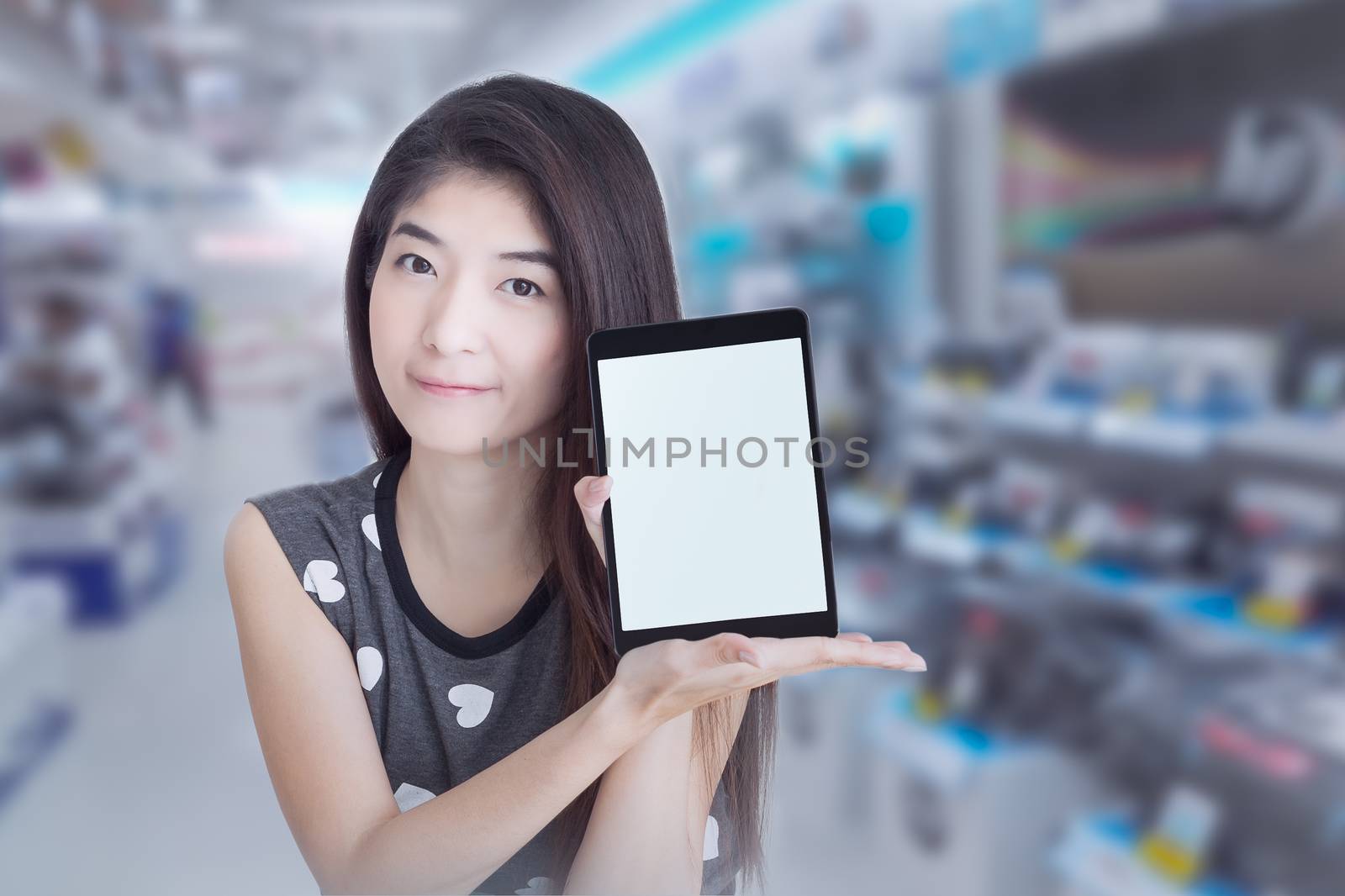 Young Asian woman show or display tablet with blank screen on shopping mall background