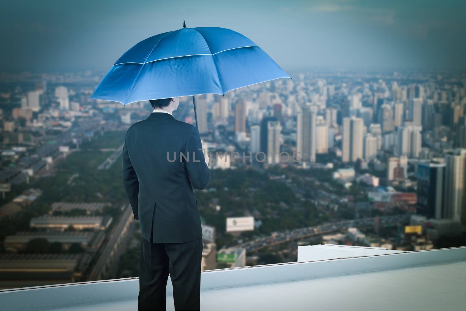 Back view of businessman with umbrella on the rooftop and lookin by FrameAngel