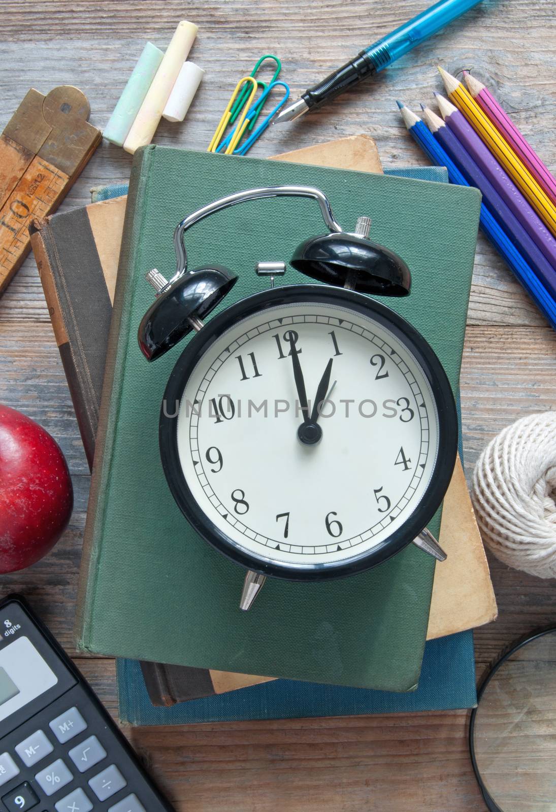 Clock on top of a book and various school and stationery accessories 