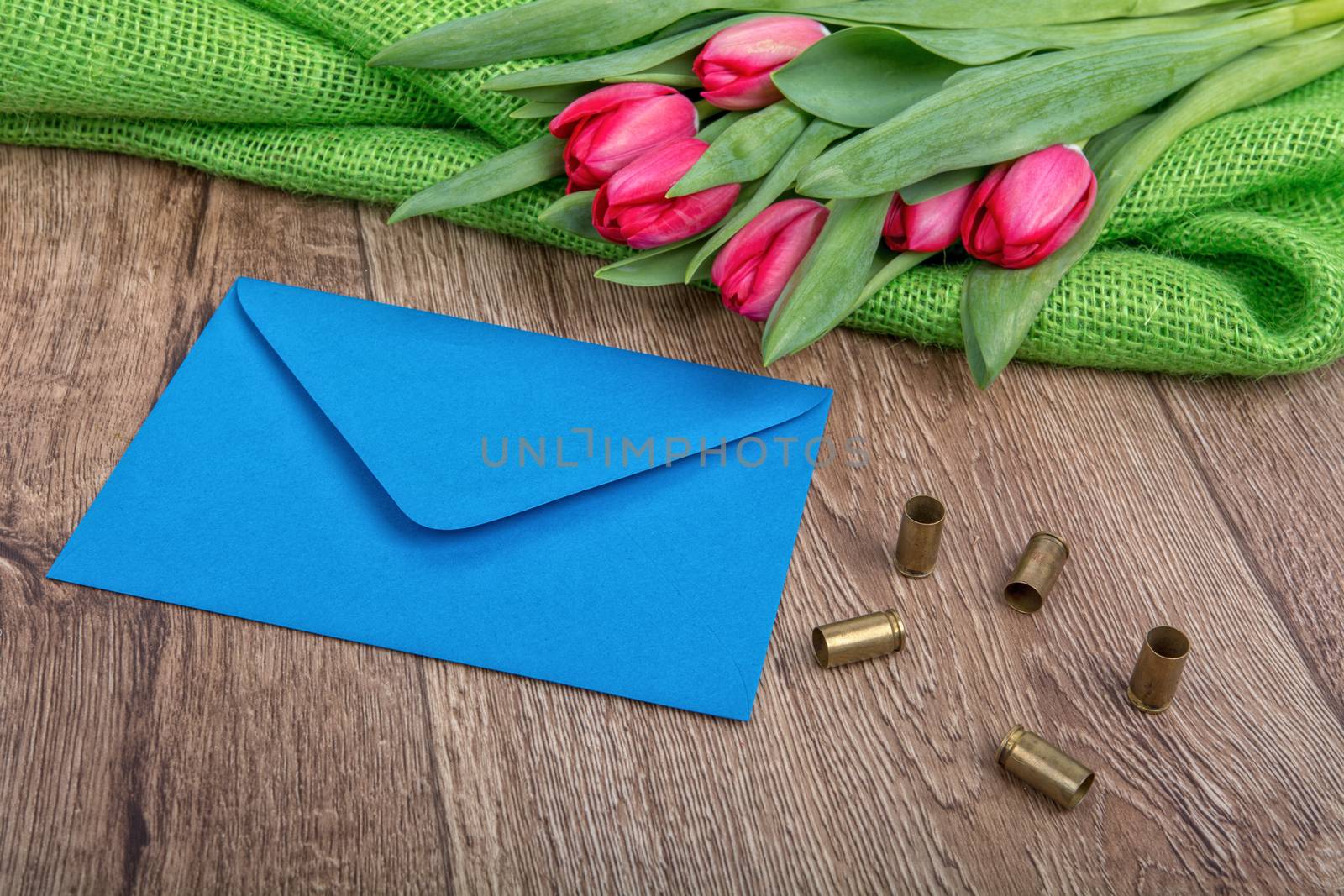 Blue envelope, tulips and bullets on a wooden background