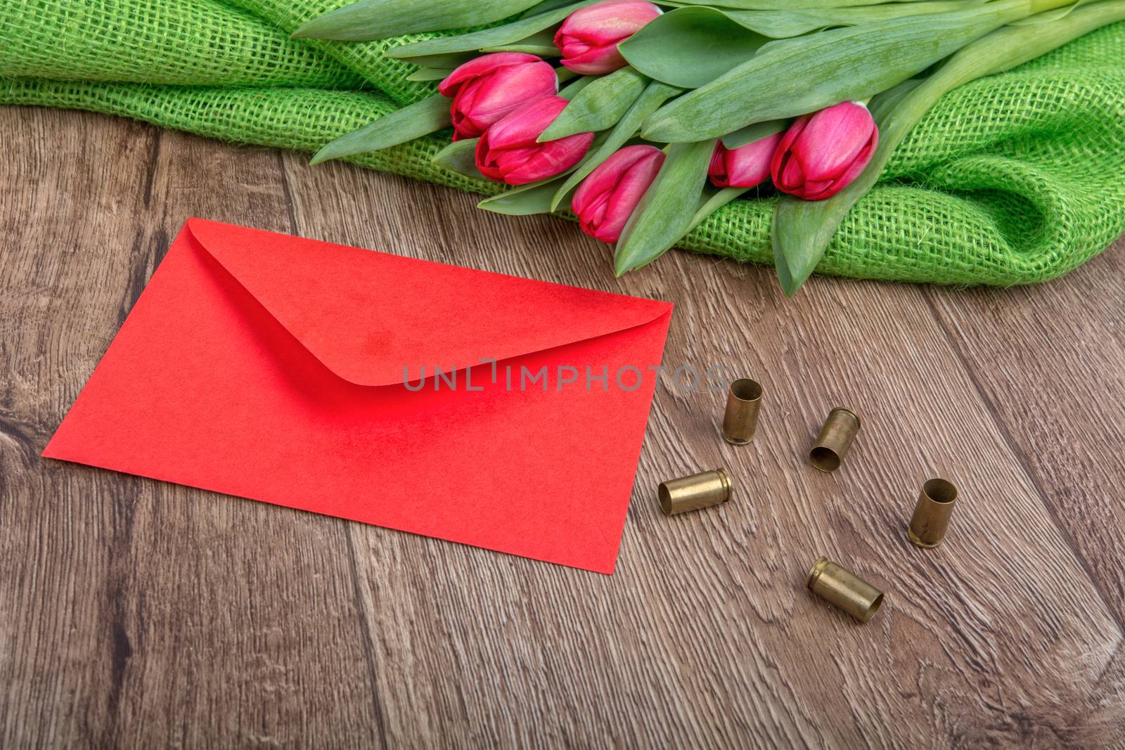 Red envelope, tulips and bullets on a wooden background