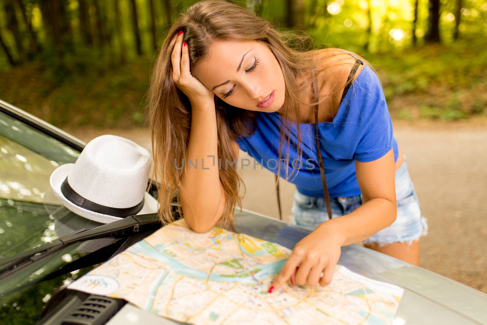 Confused lost beautiful woman standing leaning at car in the forest and worried looking a map.