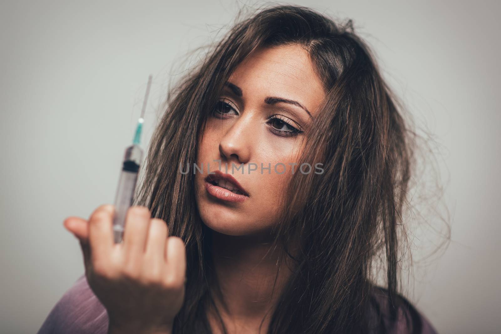 Portrait of a beautiful girl drug addiction. She is holding syringe with drugs.