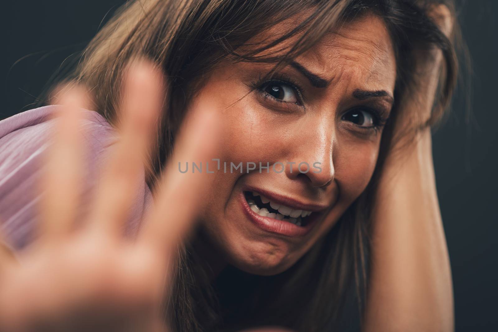 Young abused woman defending with pray looking at camera with outstretched arm. Selective focus. Focus on background, on woman face.