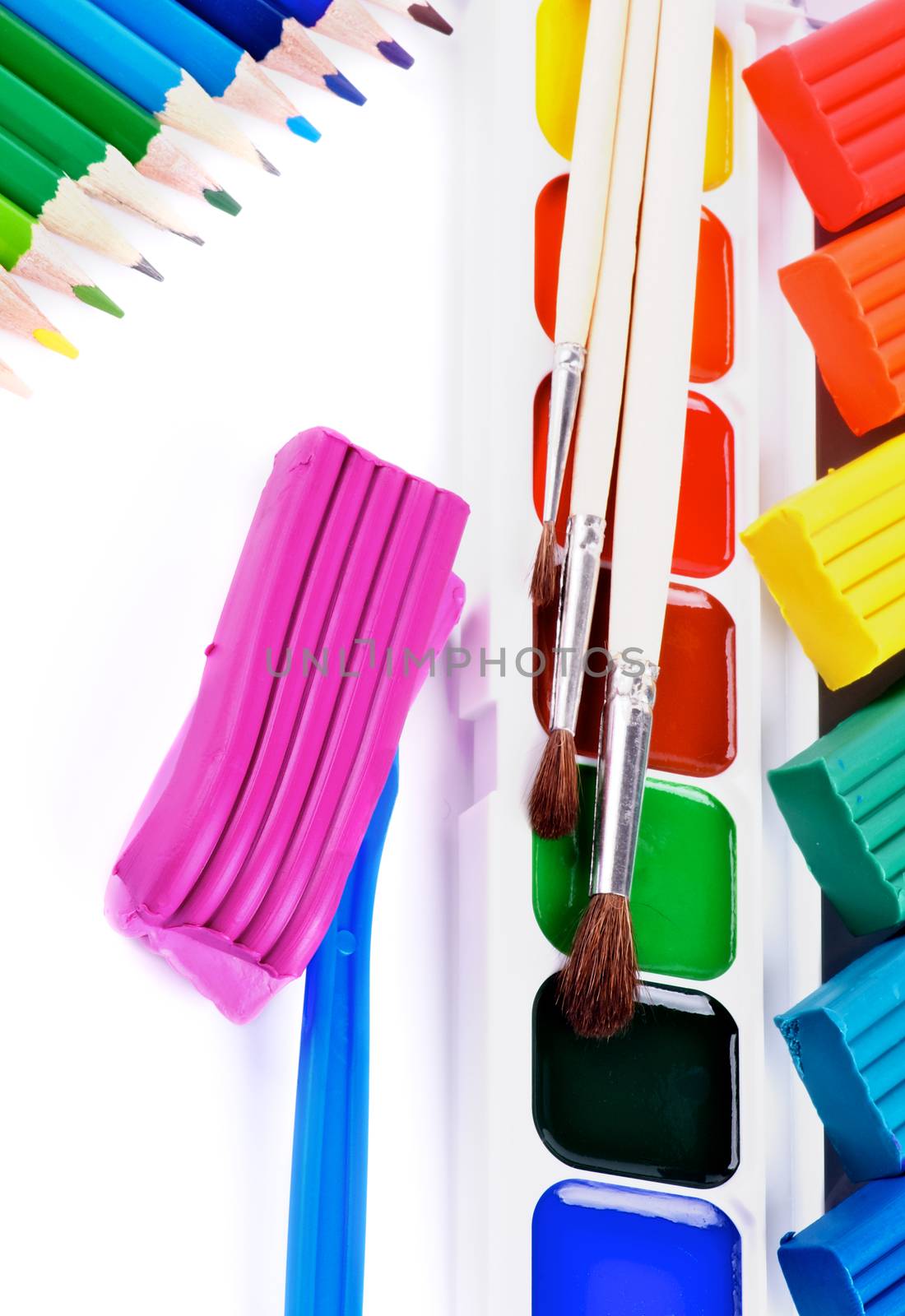 Arrangement of Watercolor Paints, Paint Brushes, Multi Colored Clay and Colored Pencils isolated on White background