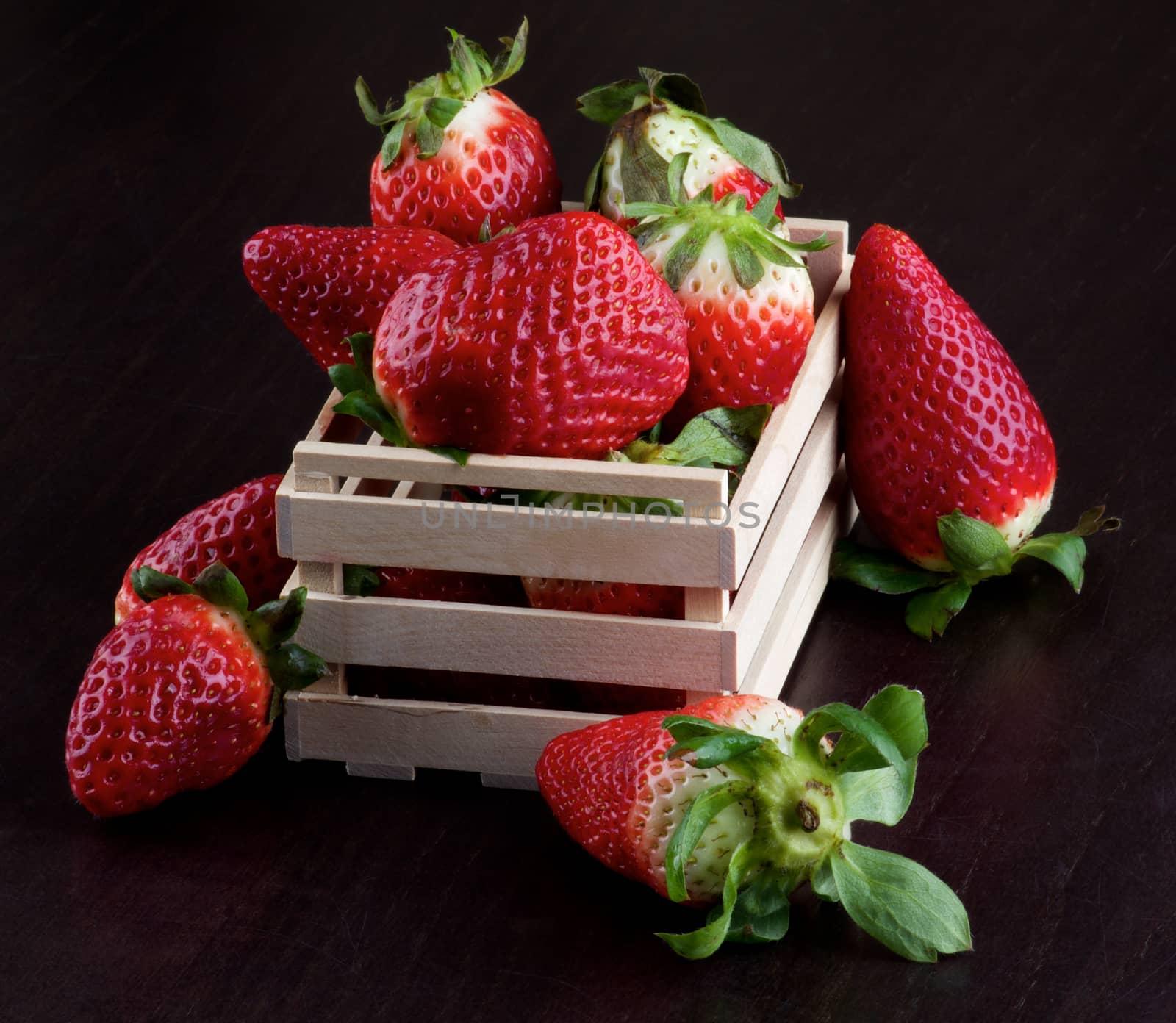 Arrangement of Fresh Ripe Strawberries in Wooden Box closeup on Dark Wooden background