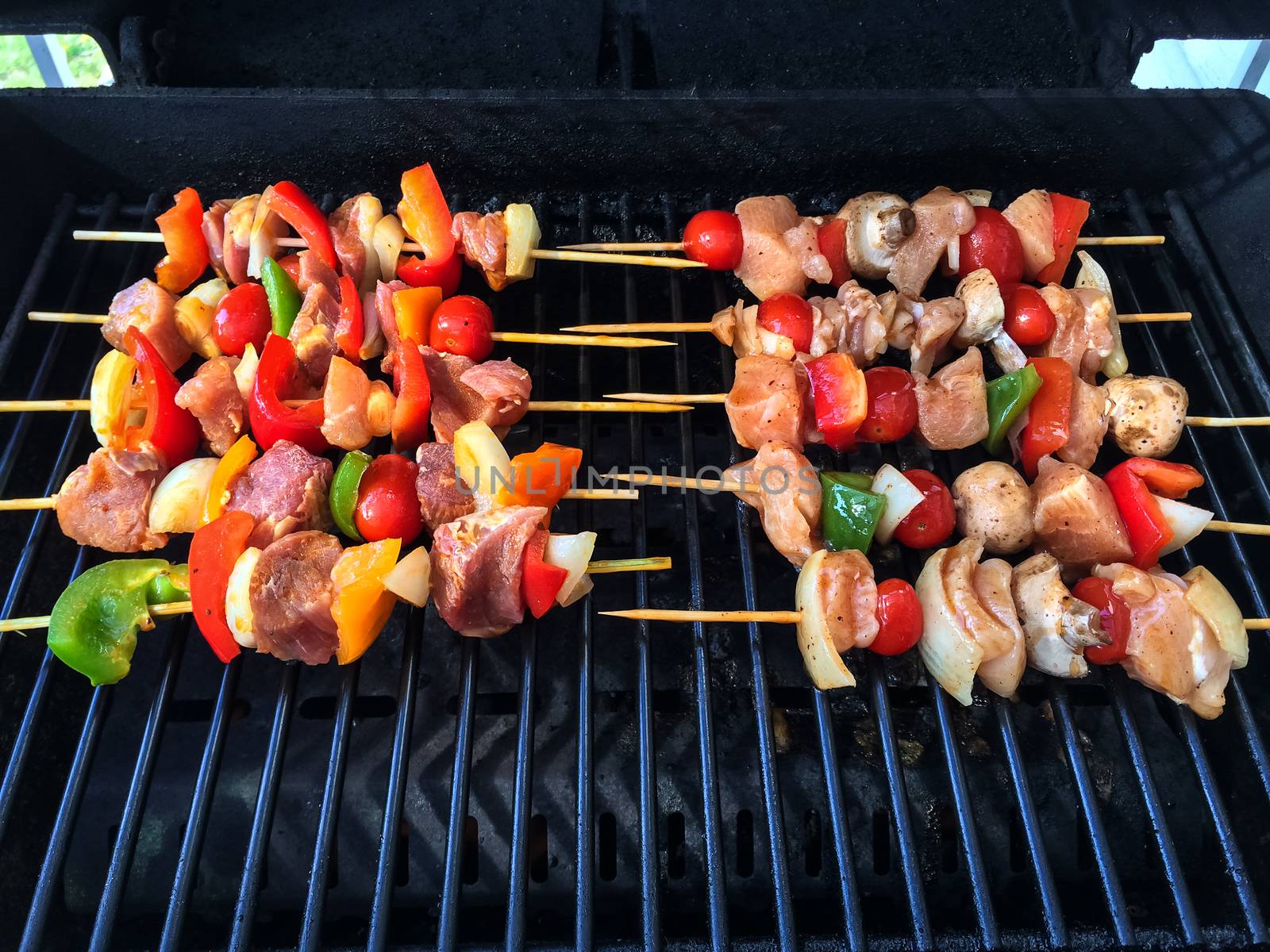 Outdoor grill with meat and vegetable skewers, ready to barbecue.