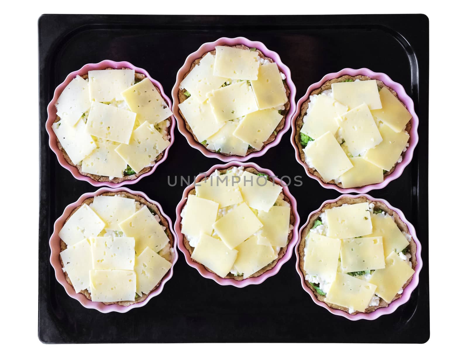 Cheese and broccoli pies on a baking tray . Cooking process. Isolated on white.