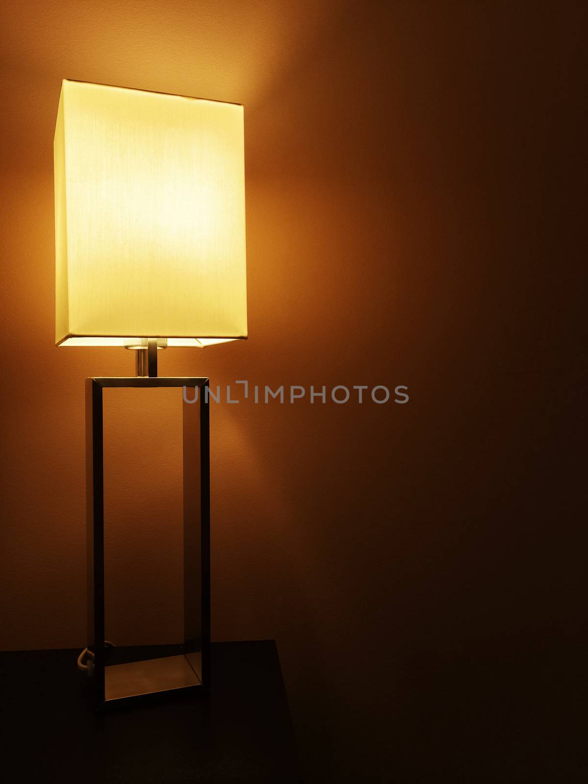 Illuminated modern table lamp in a dark room.