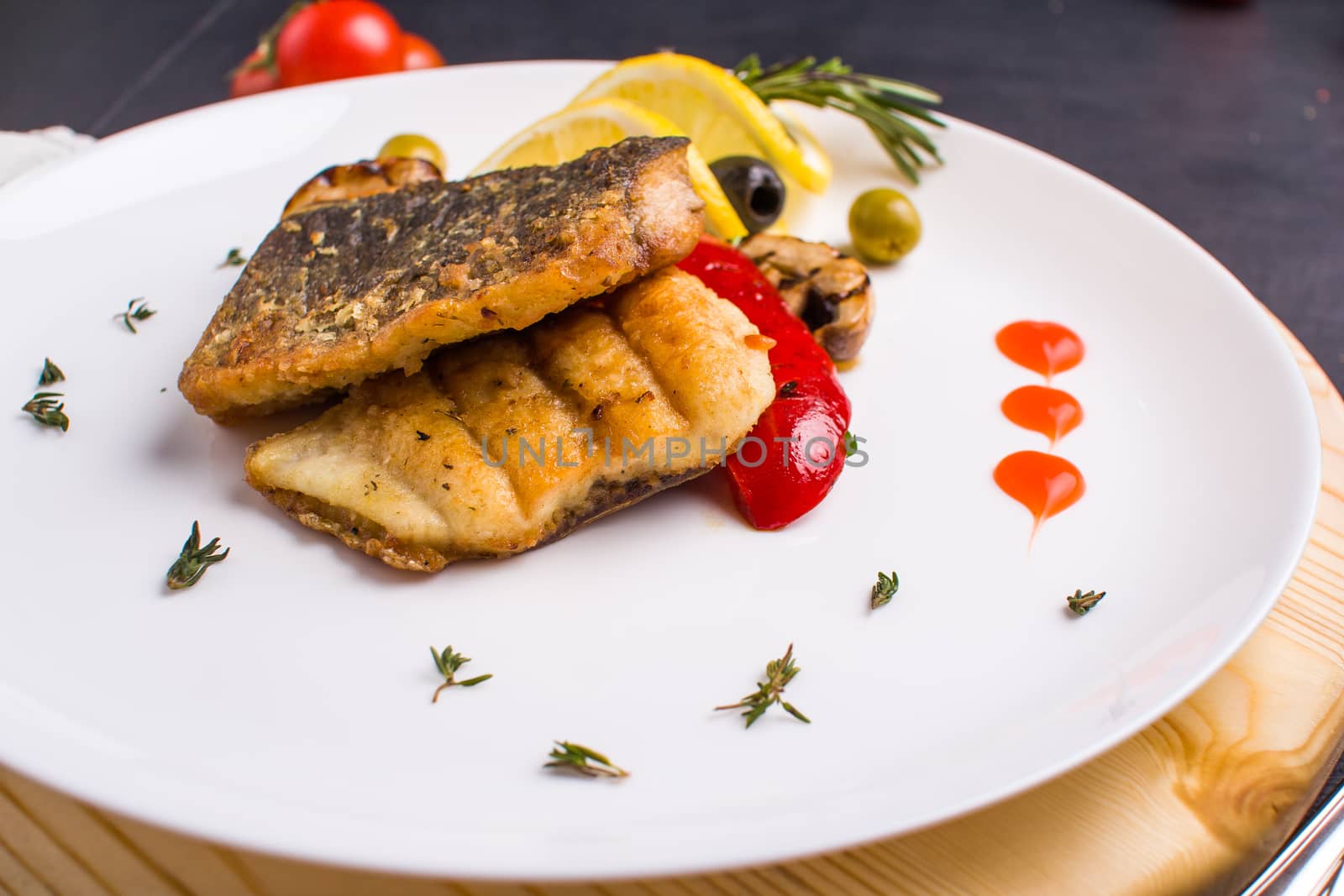 Concept: healthy food. Homemade grilled fish steak and vegetables on a plate with ingredients and cutlery around