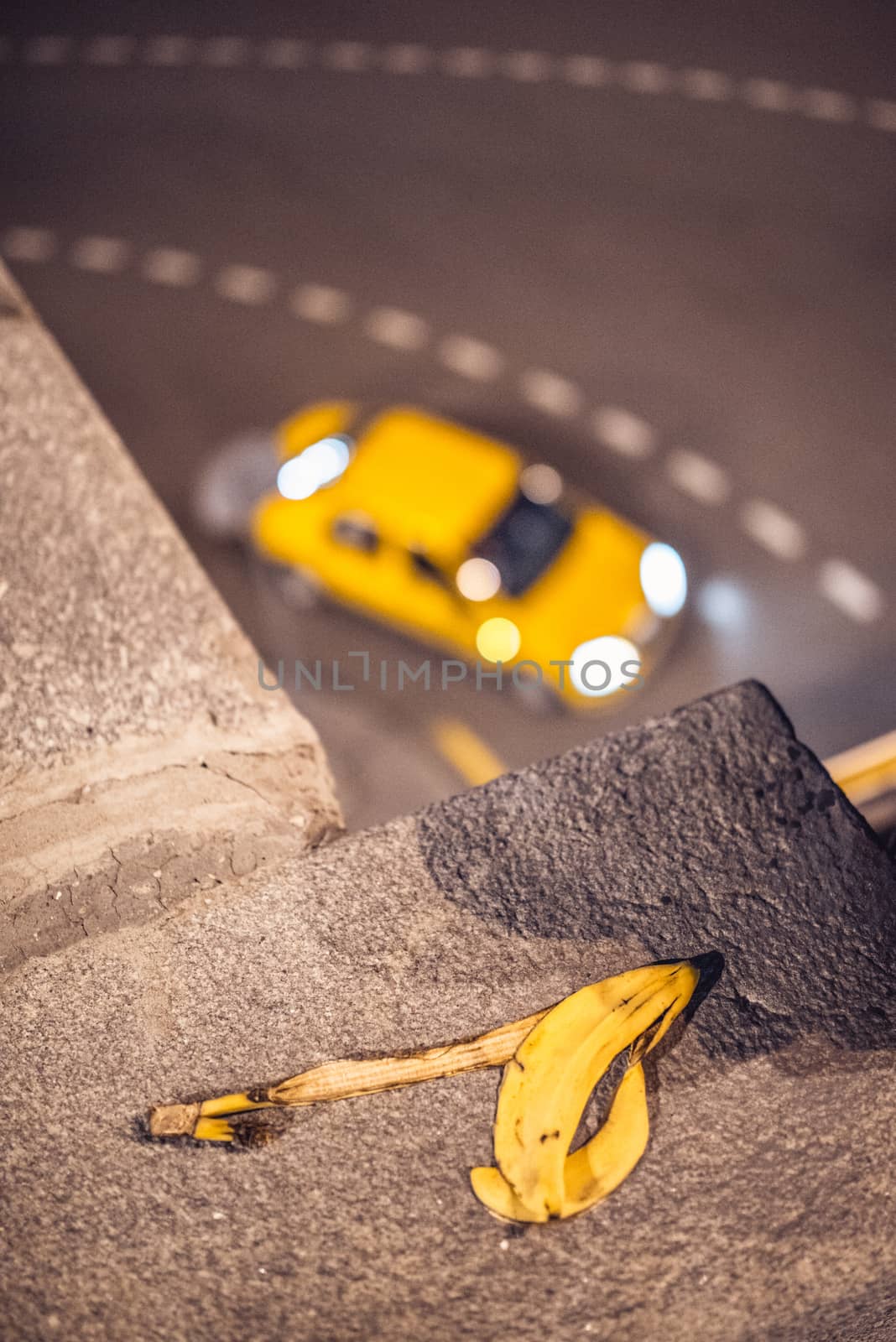 yellow taxi cab passing corner on the blurred background with banana skin in front