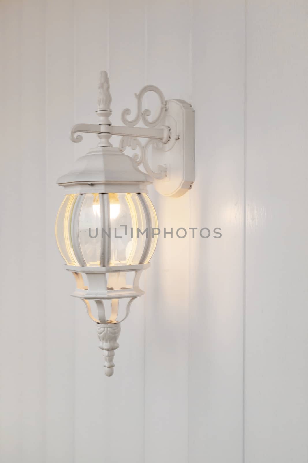 the metal white forged candelabrum on a white wooden wall