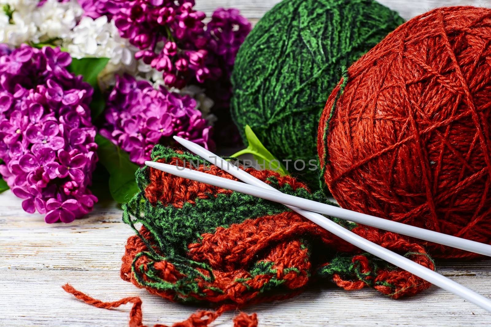 Balls of wool yarn for knitting and branches of lilac blossoms