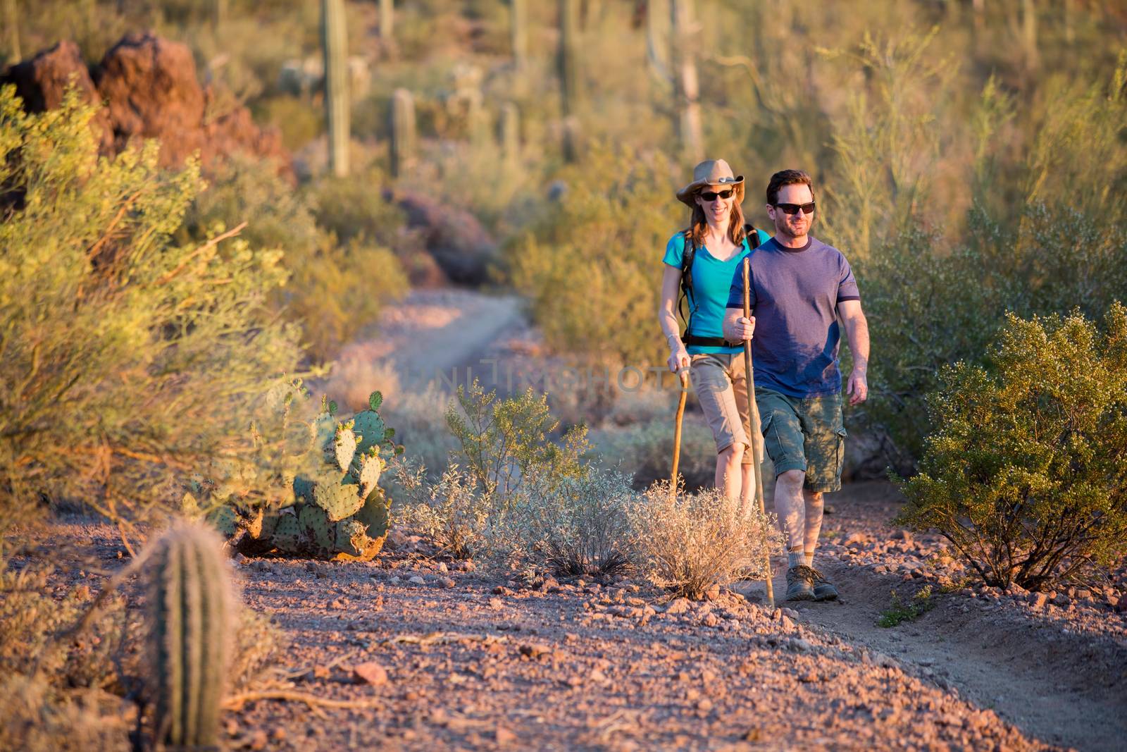 Two Afternoon Hikers on Rugged Desert Trail by Creatista