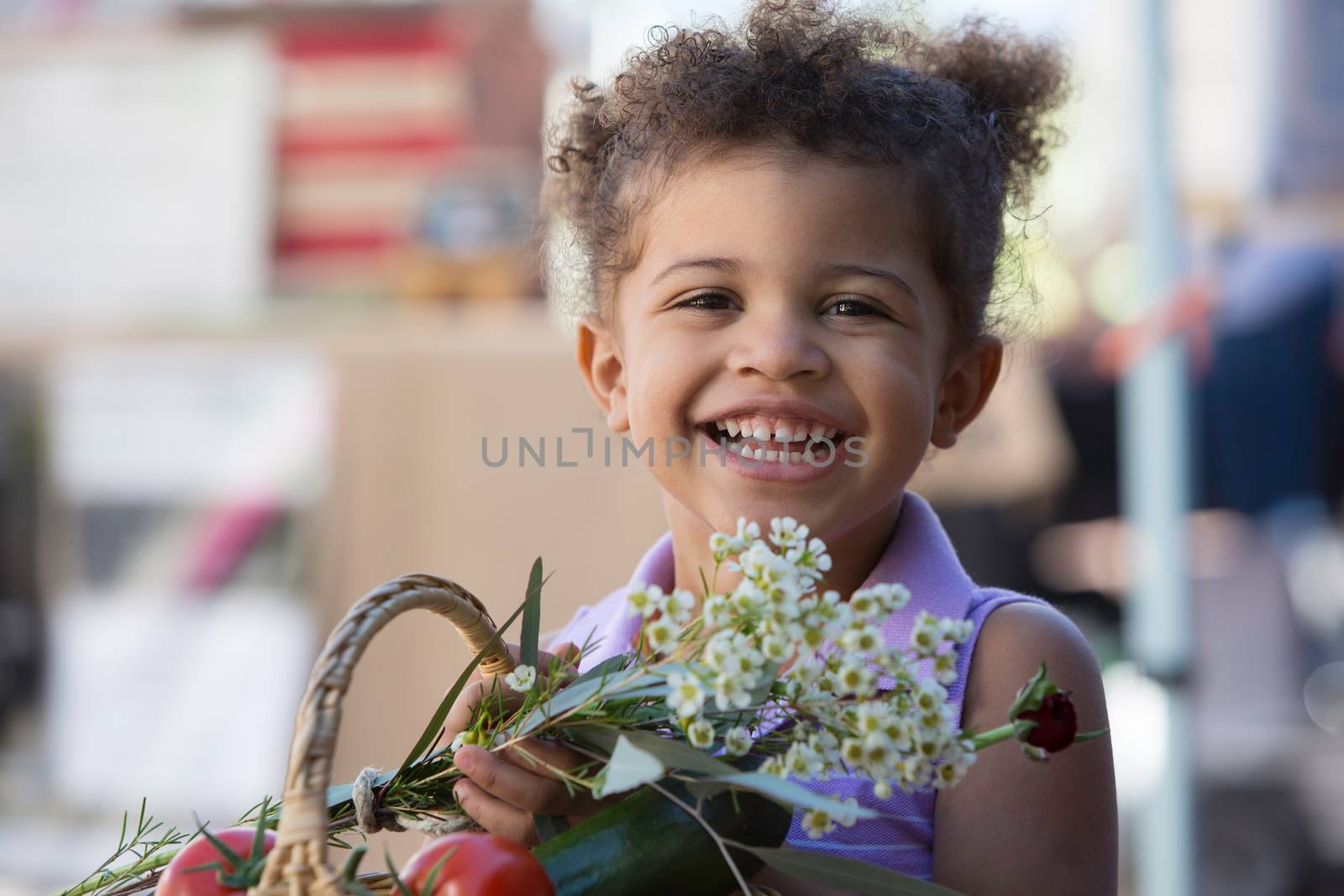 Cute young girl with basket of produce at farmers market