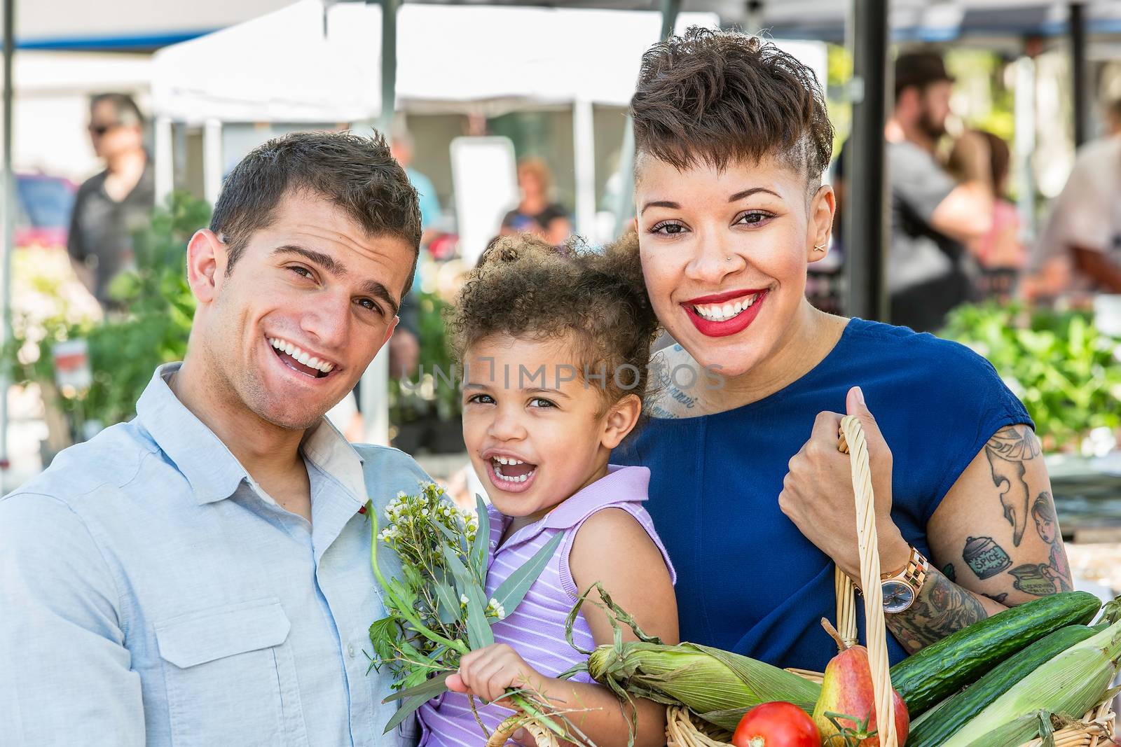Smiling family with basket of produce at farmers market