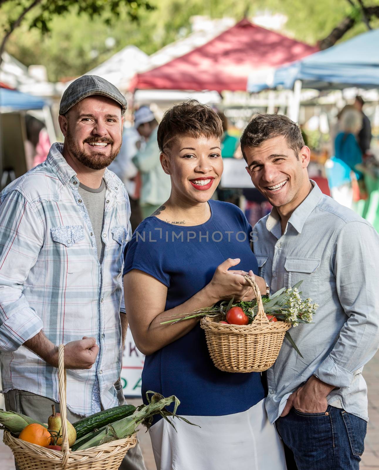 Smiling friends with baskets of produce at farmers market