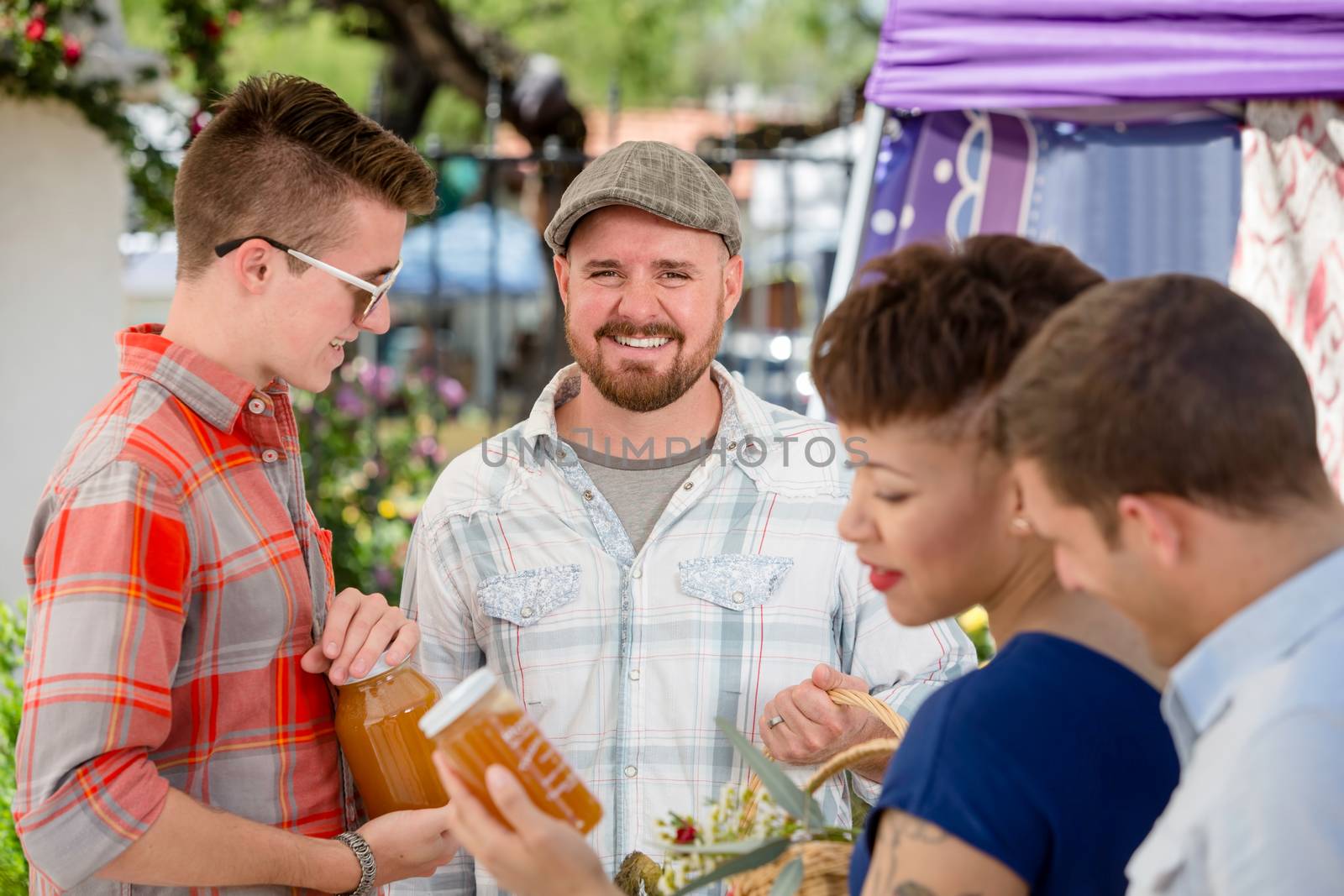 Handsome man with honey vendor at outdoor farmers market