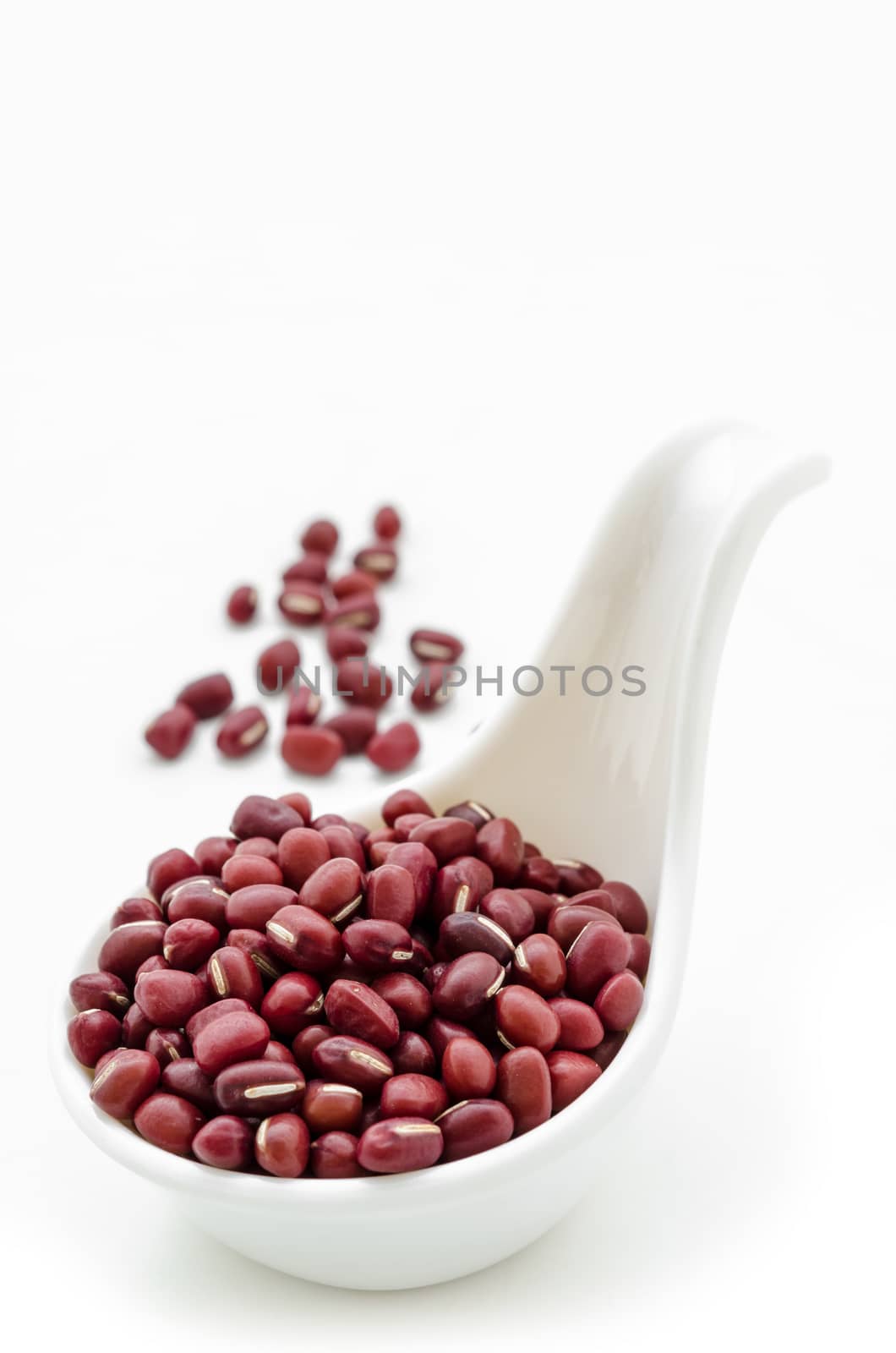 Raw azuki beans on white spoon over white background