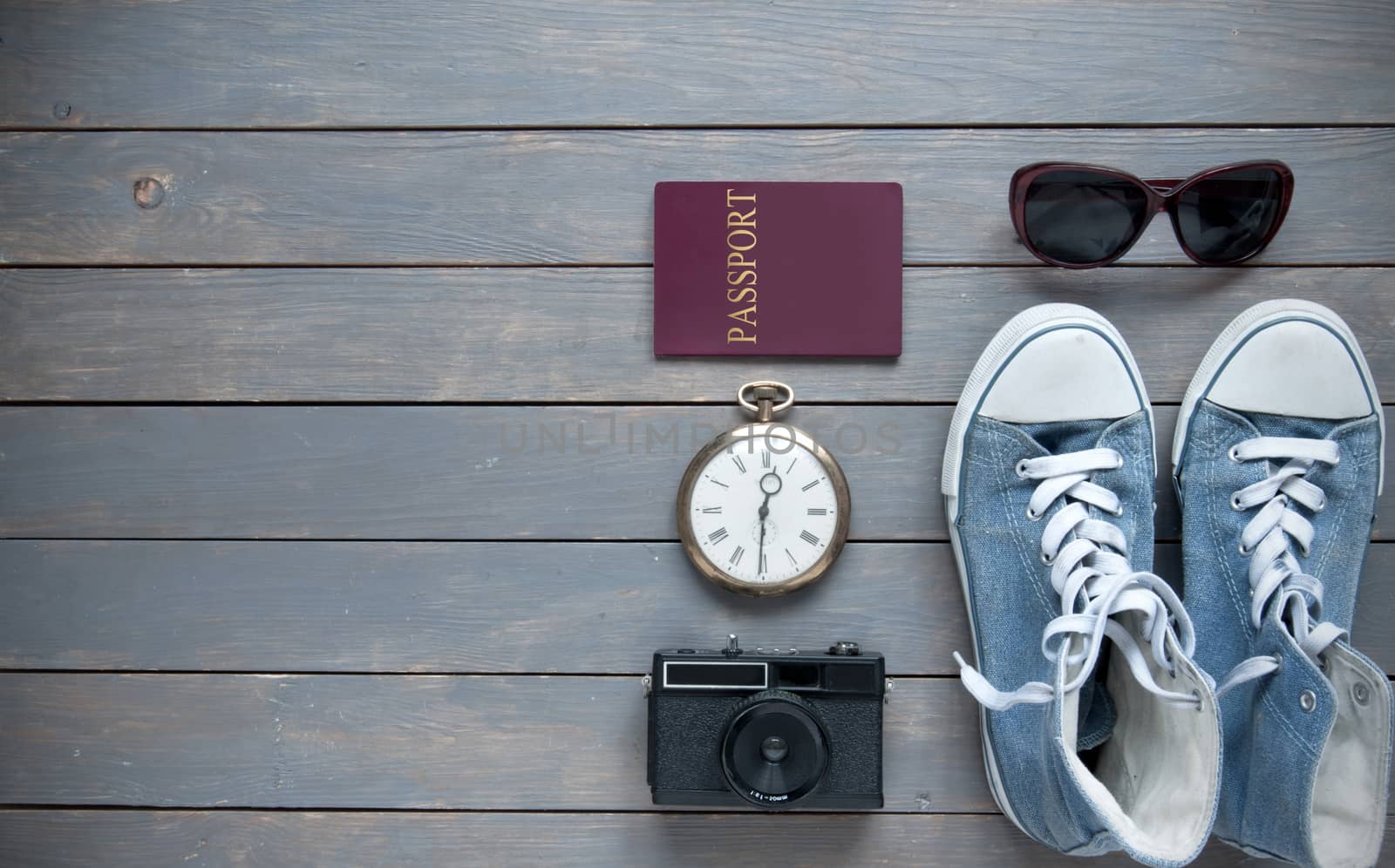 Closeup of travel items on a wooden background with passport, camera and shoes 