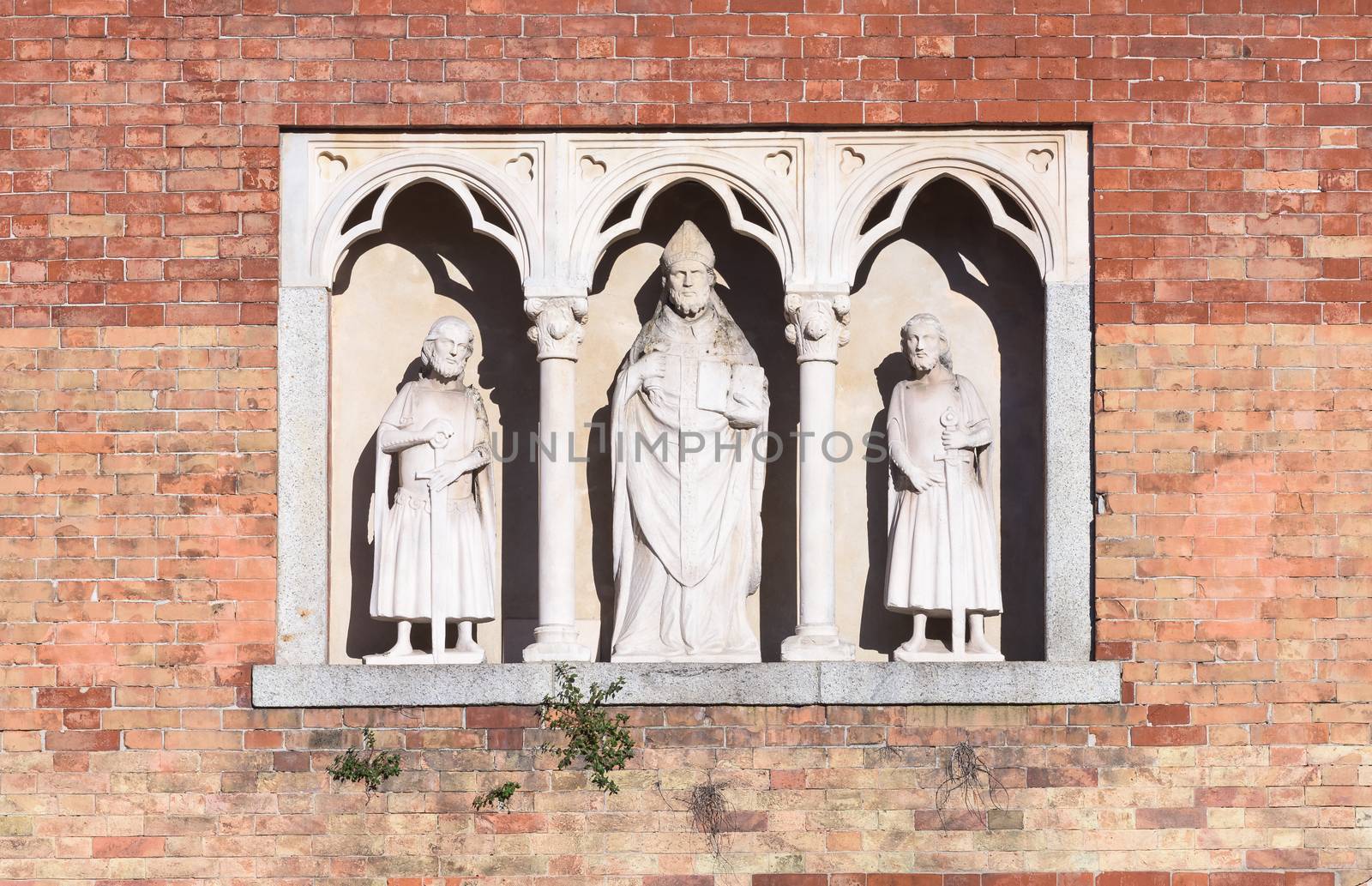 In the picture three statues, located in the center the statue of Saint Ambrose, Milan, Italy.