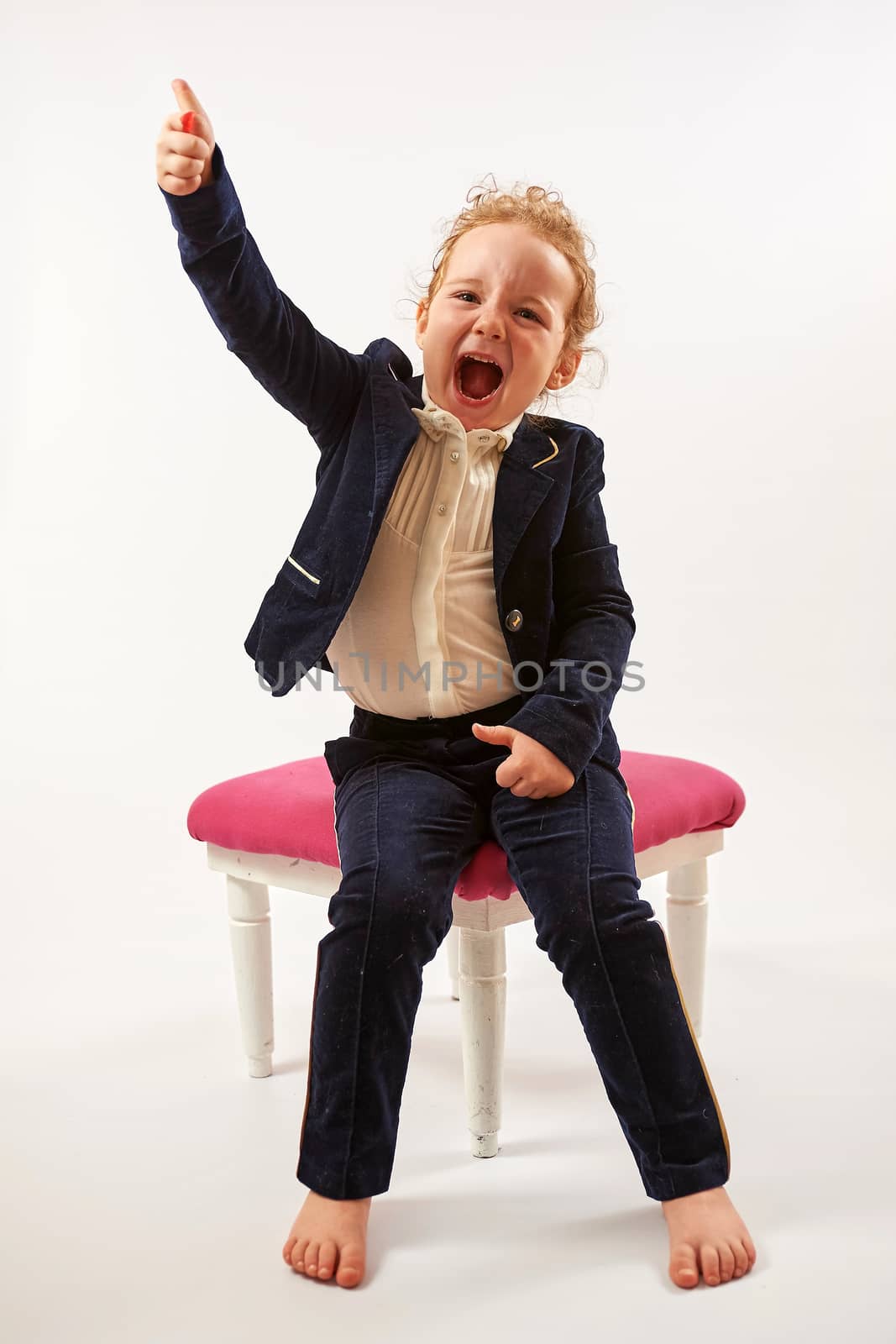 Little girl in black suit sitting and shows up