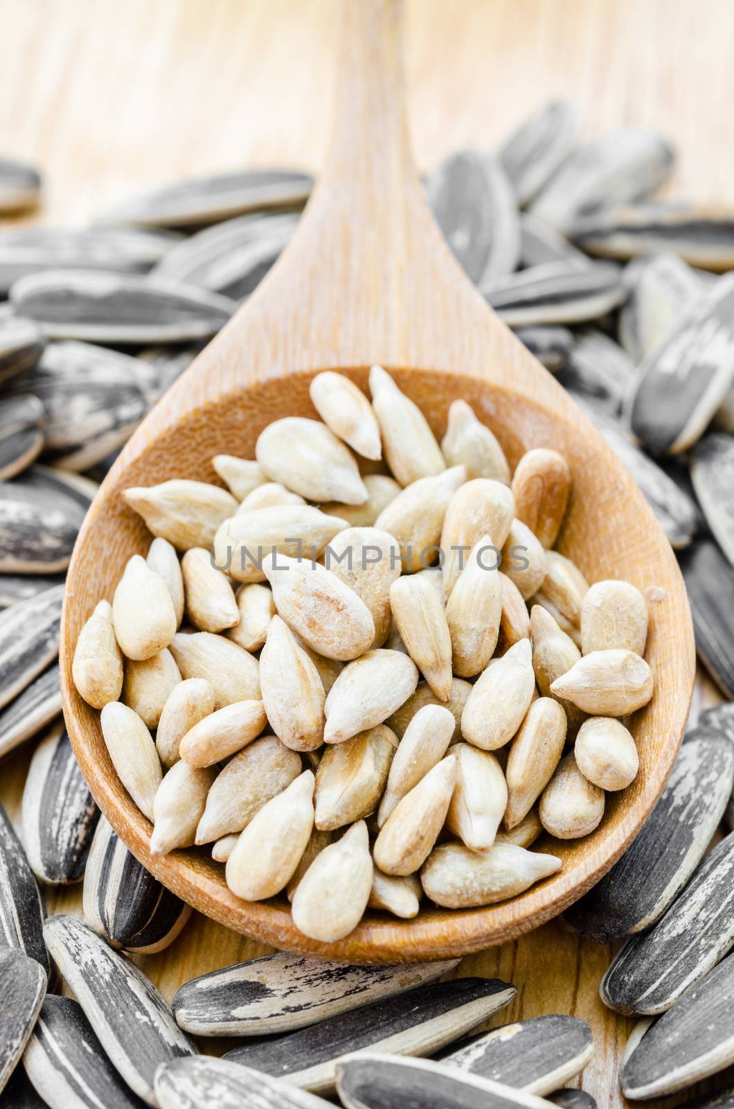 sunflower seeds in wooden spoon on wood background