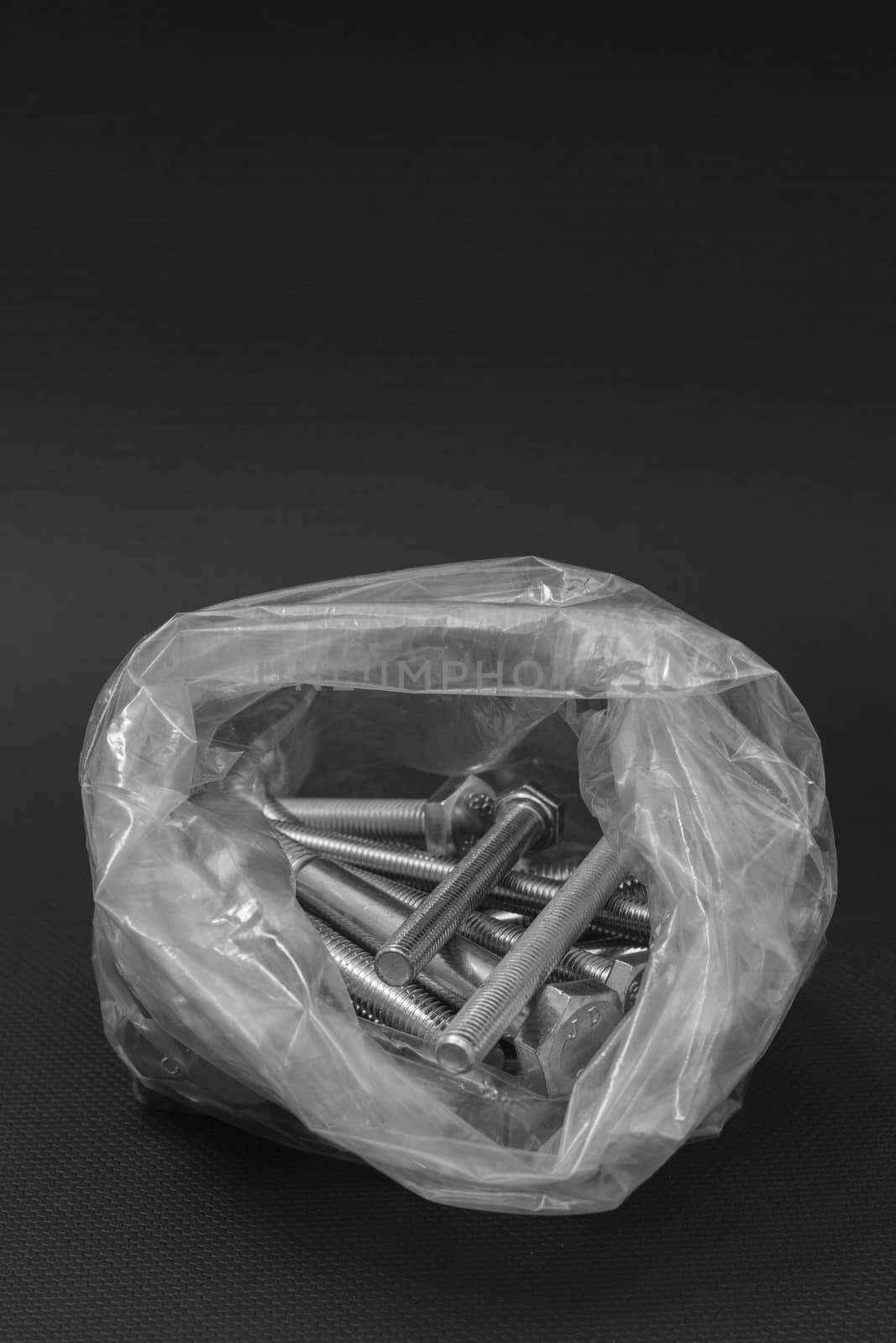 Bolts in a clear plastic bag on a black background by mailos