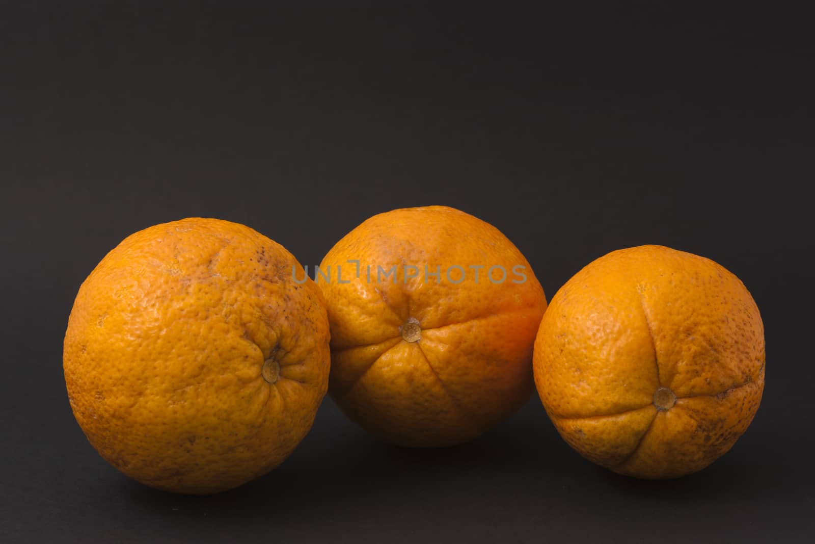 Three oranges on a black background to understand a concept for healthy eating