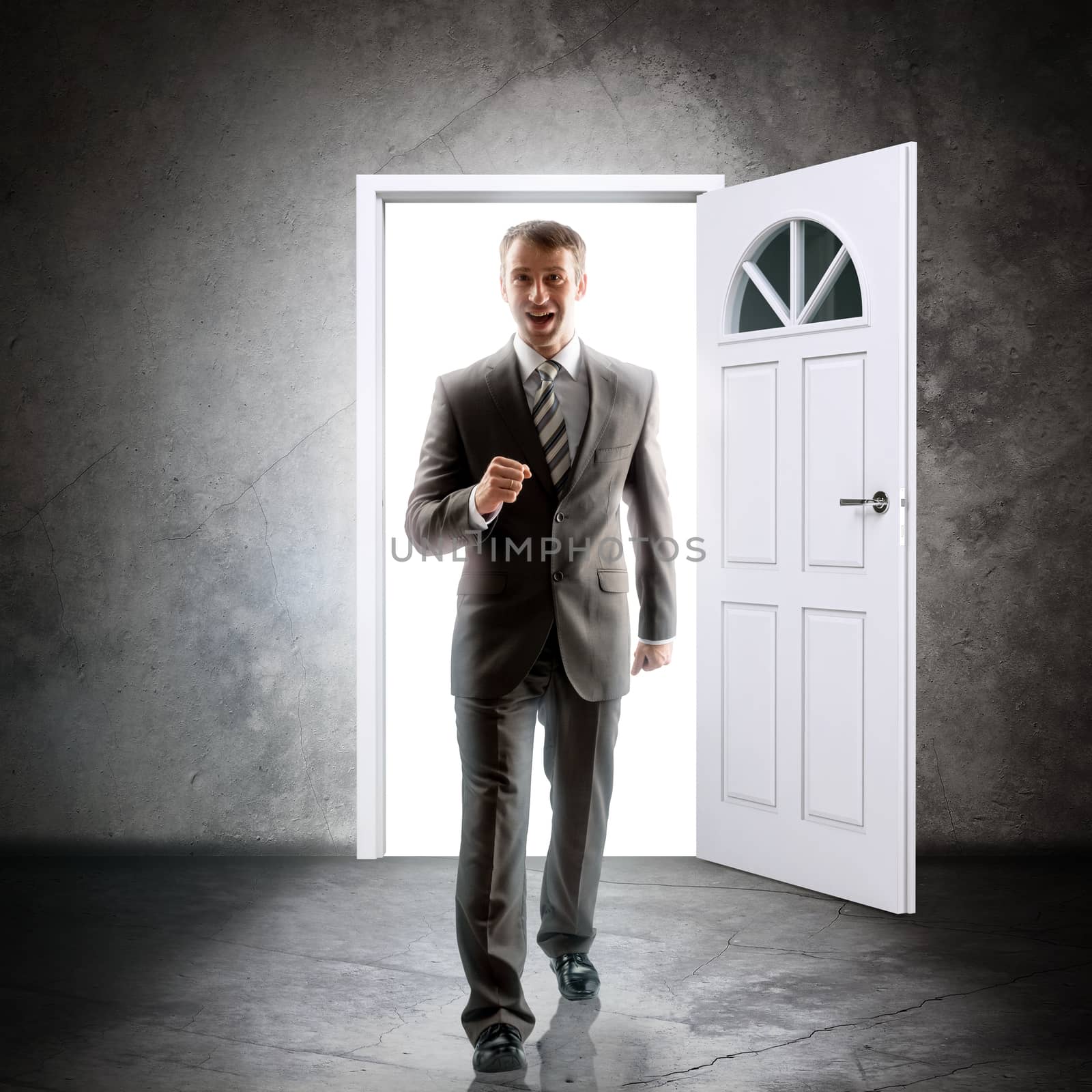 Businessman comes inside through door. Behind door bright light. Success concept 