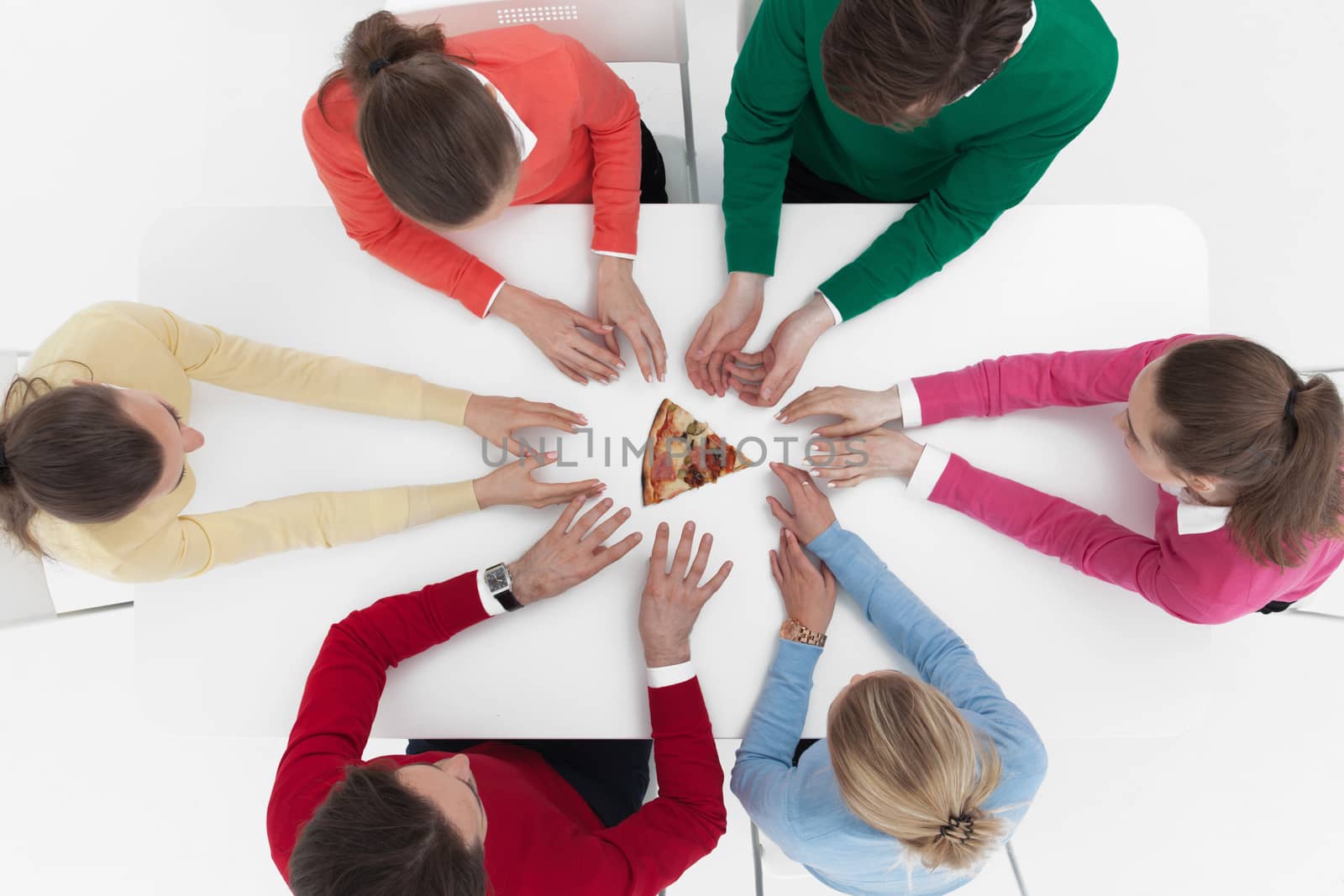 Top view of people sitting around the table and stretching hands to last piece of pizza