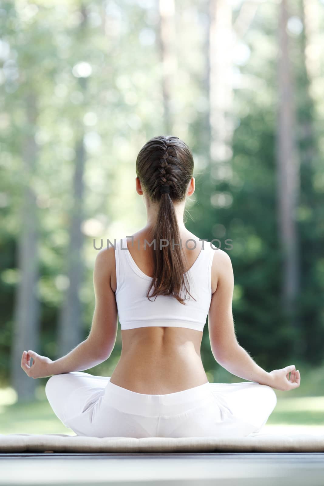 Pretty young woman doing yoga exercise in the park