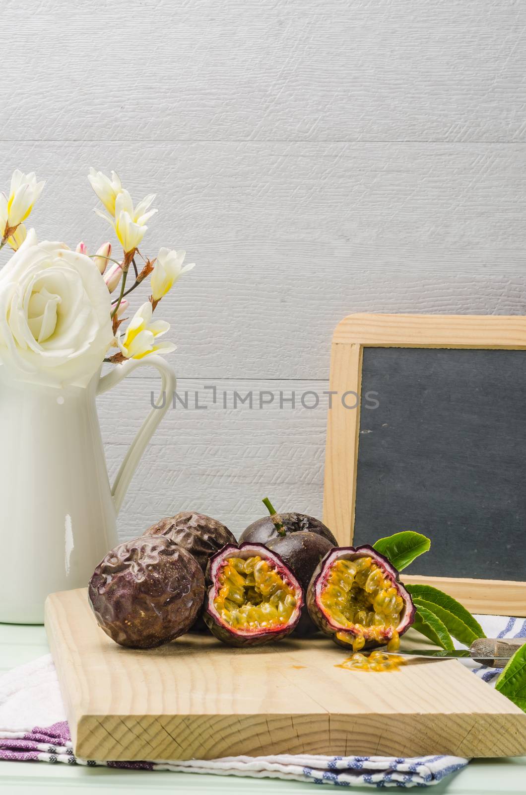 Passion fruits with leaves, knife and white flowers in jar by AnaMarques