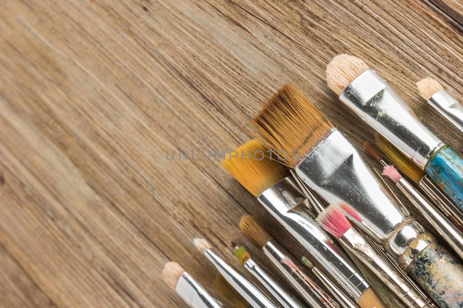 Artist paint brushes over rustic wooden texture by AnaMarques
