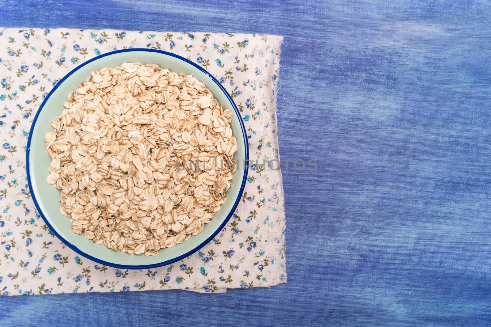 Oat flakes in a bowl on rustic textured background by AnaMarques