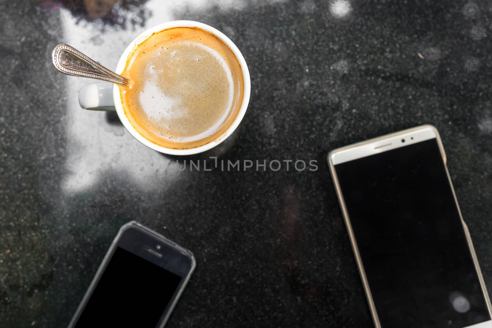 Digital smartphone and cup of coffee on desk with vintage flower. Simple coffee break in morning / selective focus